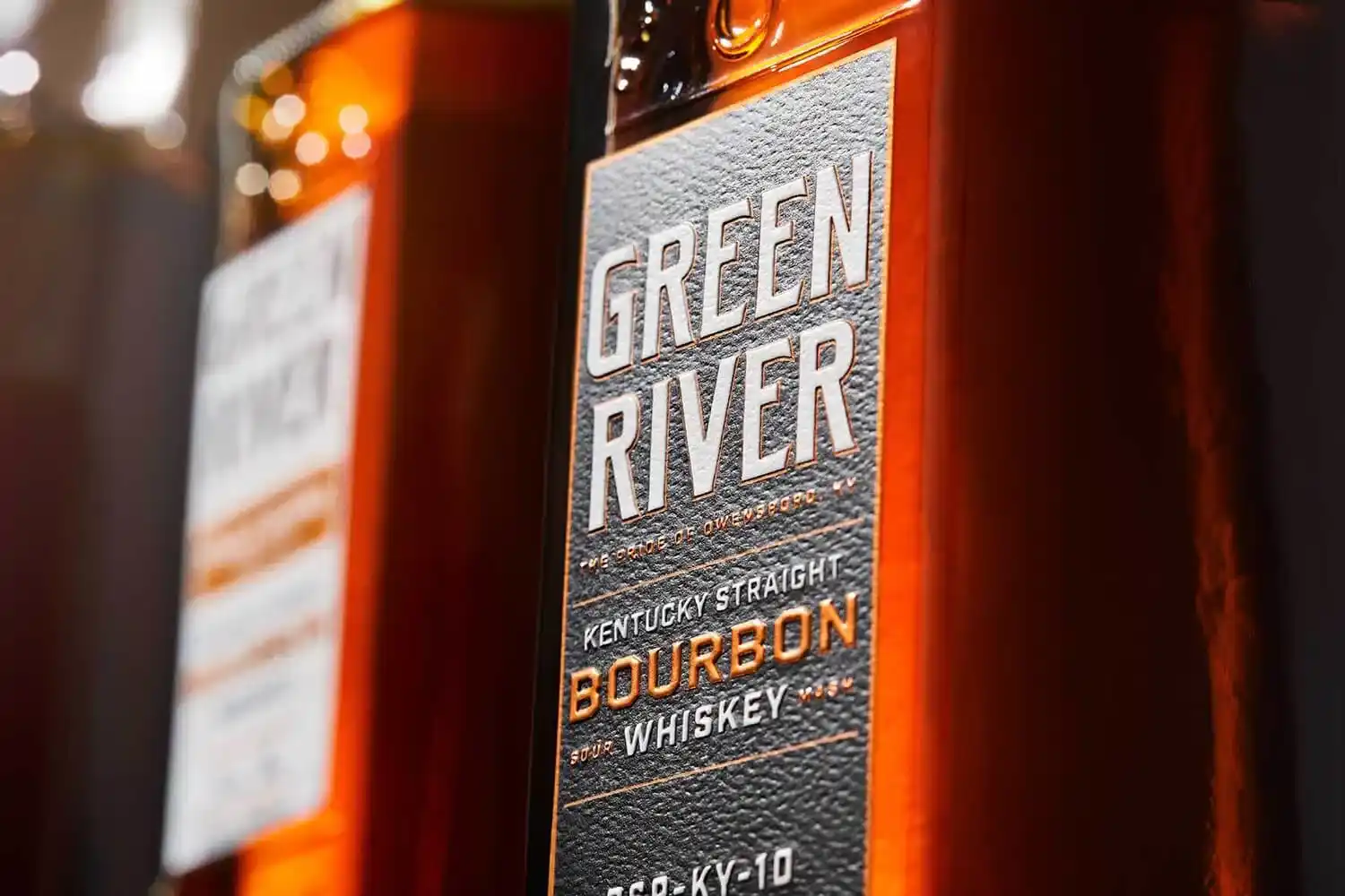 Green River Kentucky Straight Bourbon Whiskey bottle with illuminated orange label against dark background.