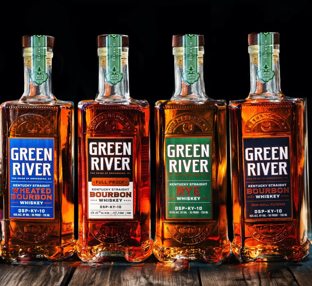 Assorted bottles of Green River Kentucky Straight Bourbon on a wooden table.