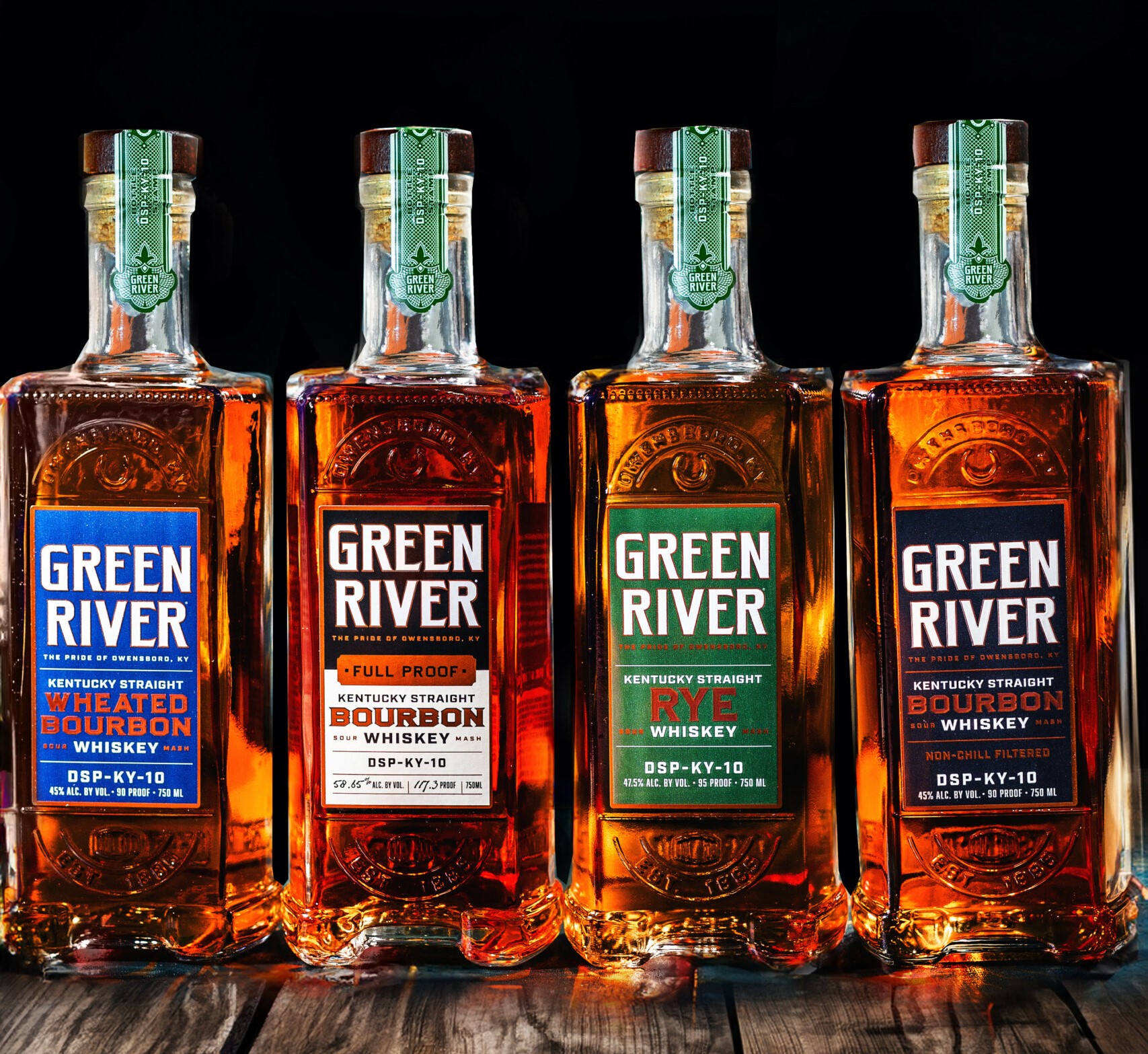 Assorted bottles of Green River Kentucky Straight Bourbon on a wooden table.