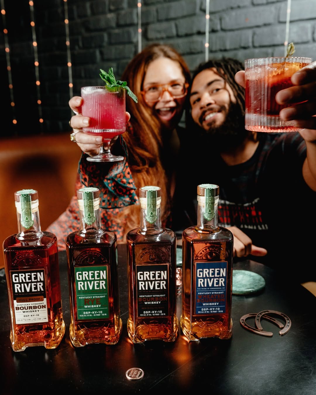 A range of whiskey bottles from Green River in front of happy customers.