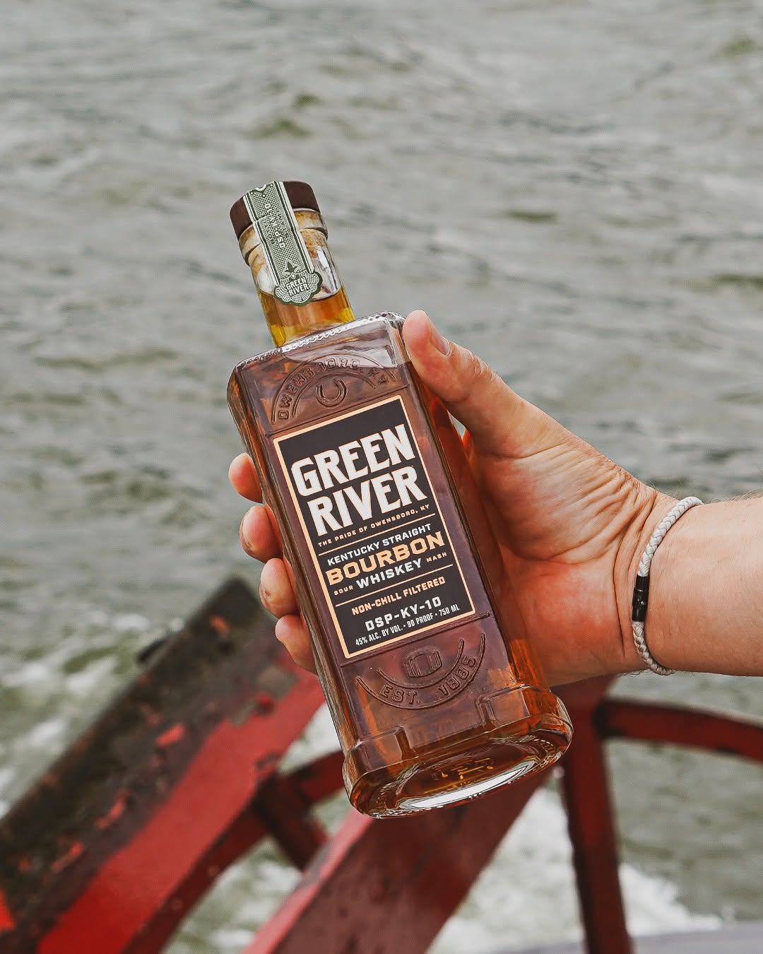 A hand holds the Kentucky Straight Bourbon Whiskey from Green River.