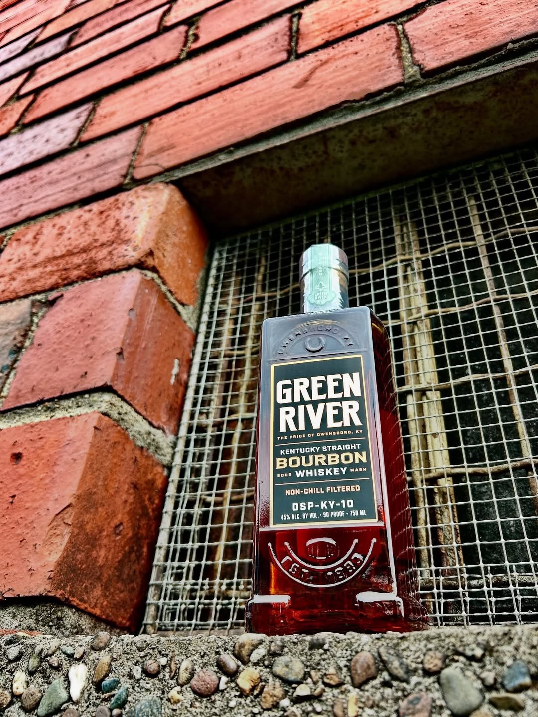 A bottle of Kentucky Straight Bourbon Whiskey from Green River on a windowsill.