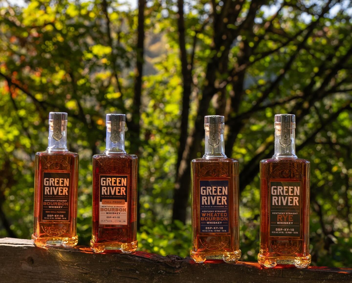 Outdoor shot of four whiskey bottles from Green River Distillery.