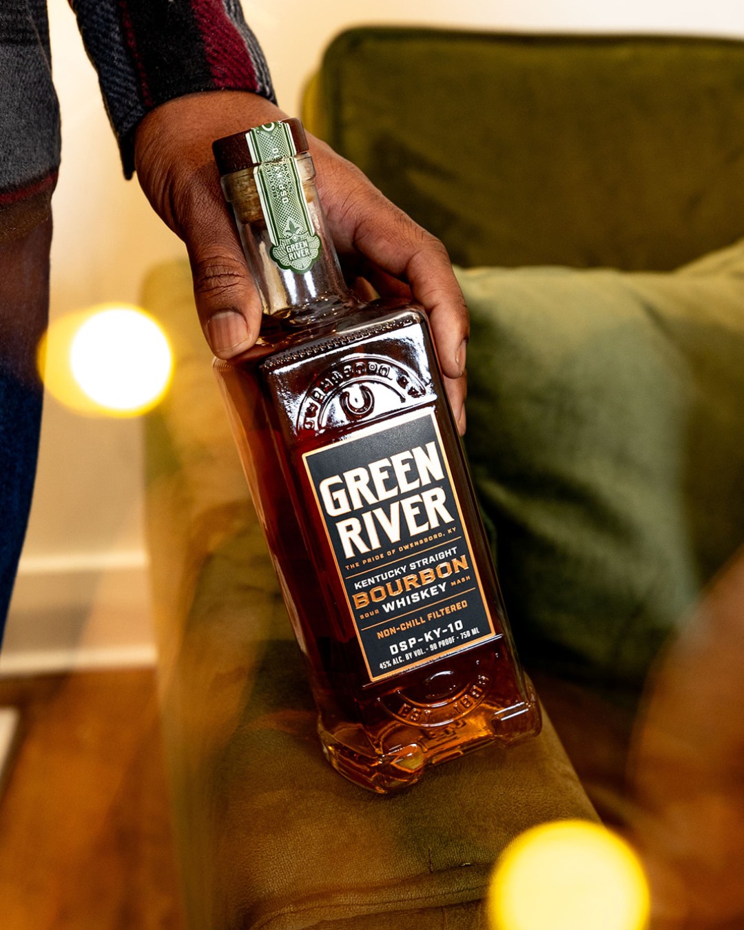 A hand holds a bottle of Kentucky Straight Bourbon Whiskey from Green River.