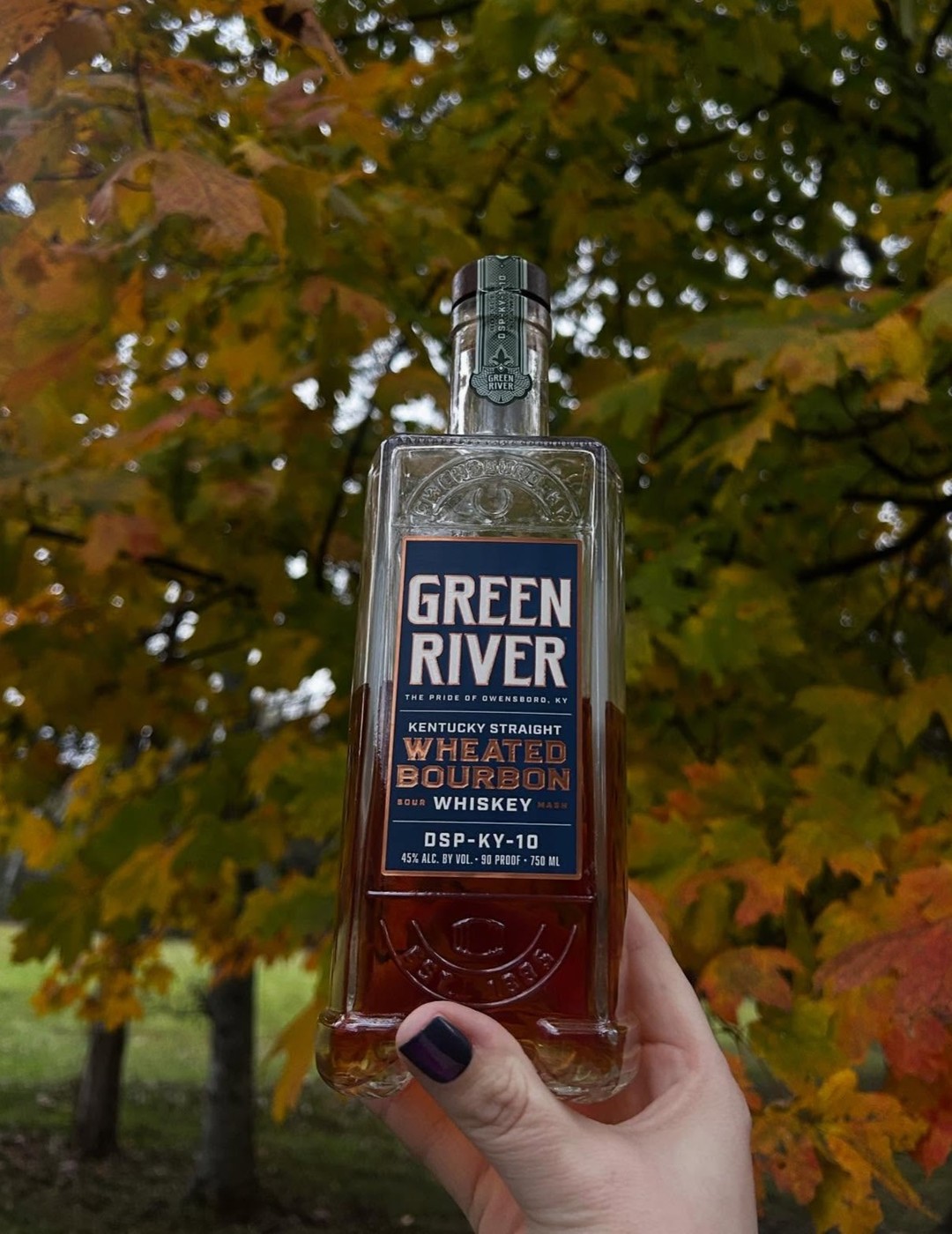 A hand holds the Kentucky Straight Wheated Bourbon Whiskey from Green River.