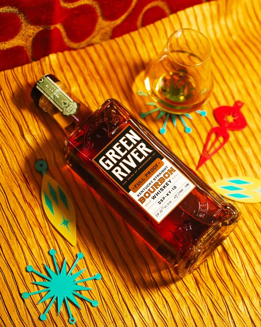 Green River Full Proof Bourbon bottle with tasting glass on a vibrant retro tabletop setting.