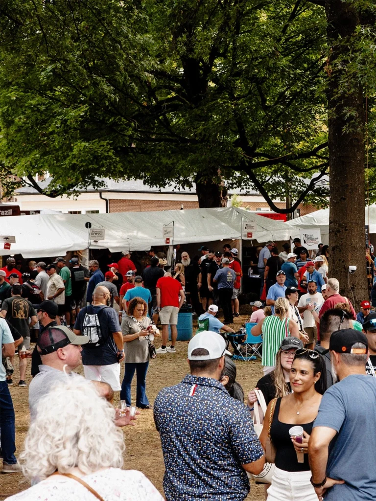 Crowd enjoying a lively Kentucky bourbon festival with tasting tents and brand booths outdoors.