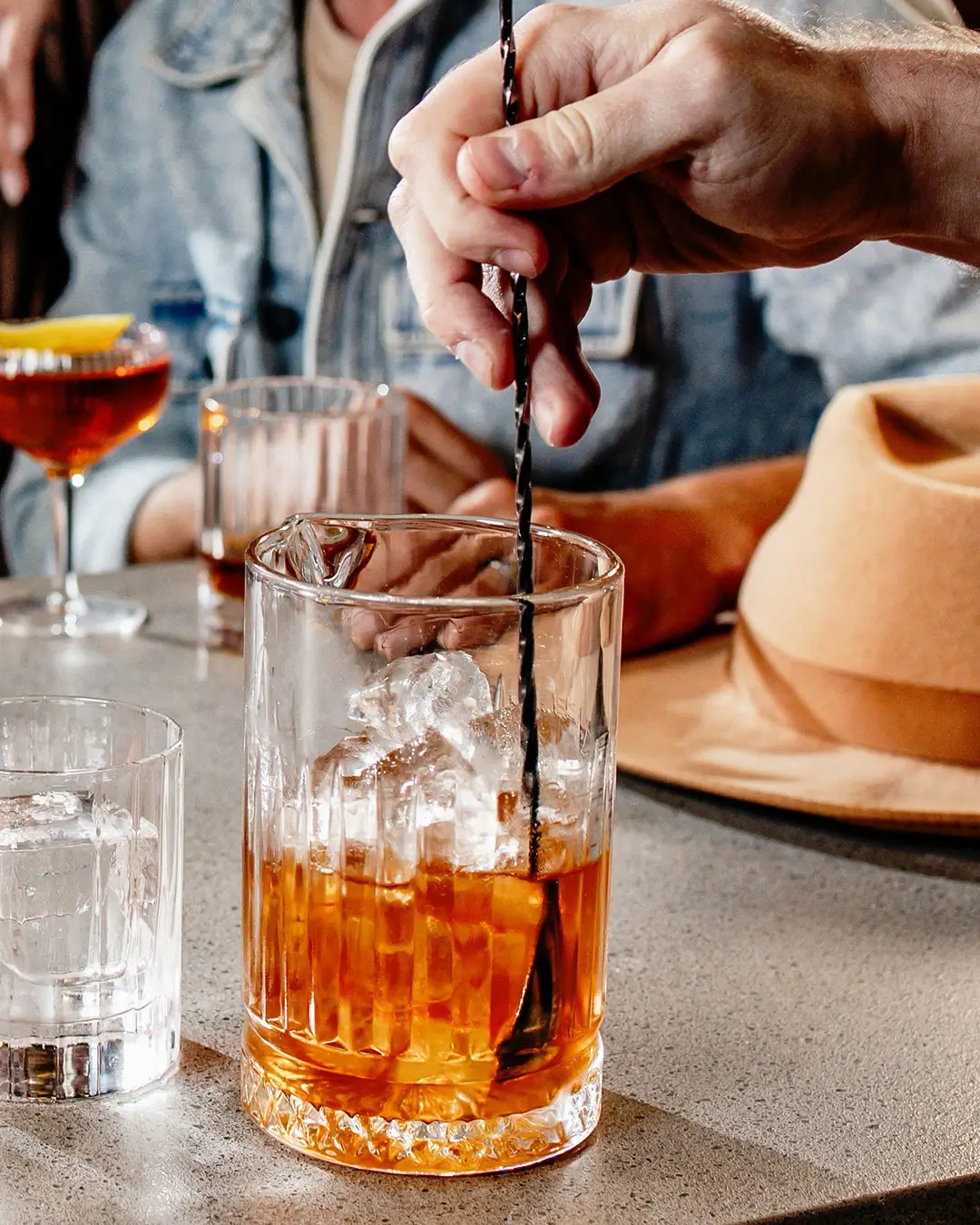 Hand stirring a whiskey cocktail over ice at the Green River tasting room bar.
