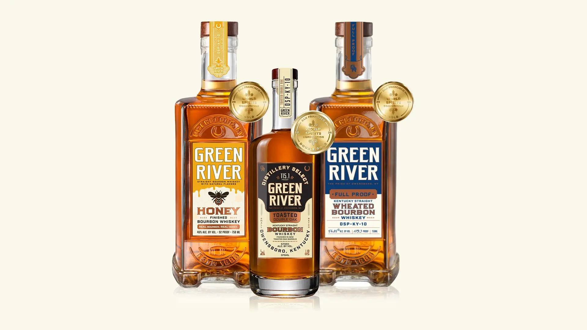 Three Green River bourbon whiskey bottles with gold award medals on a cream background.