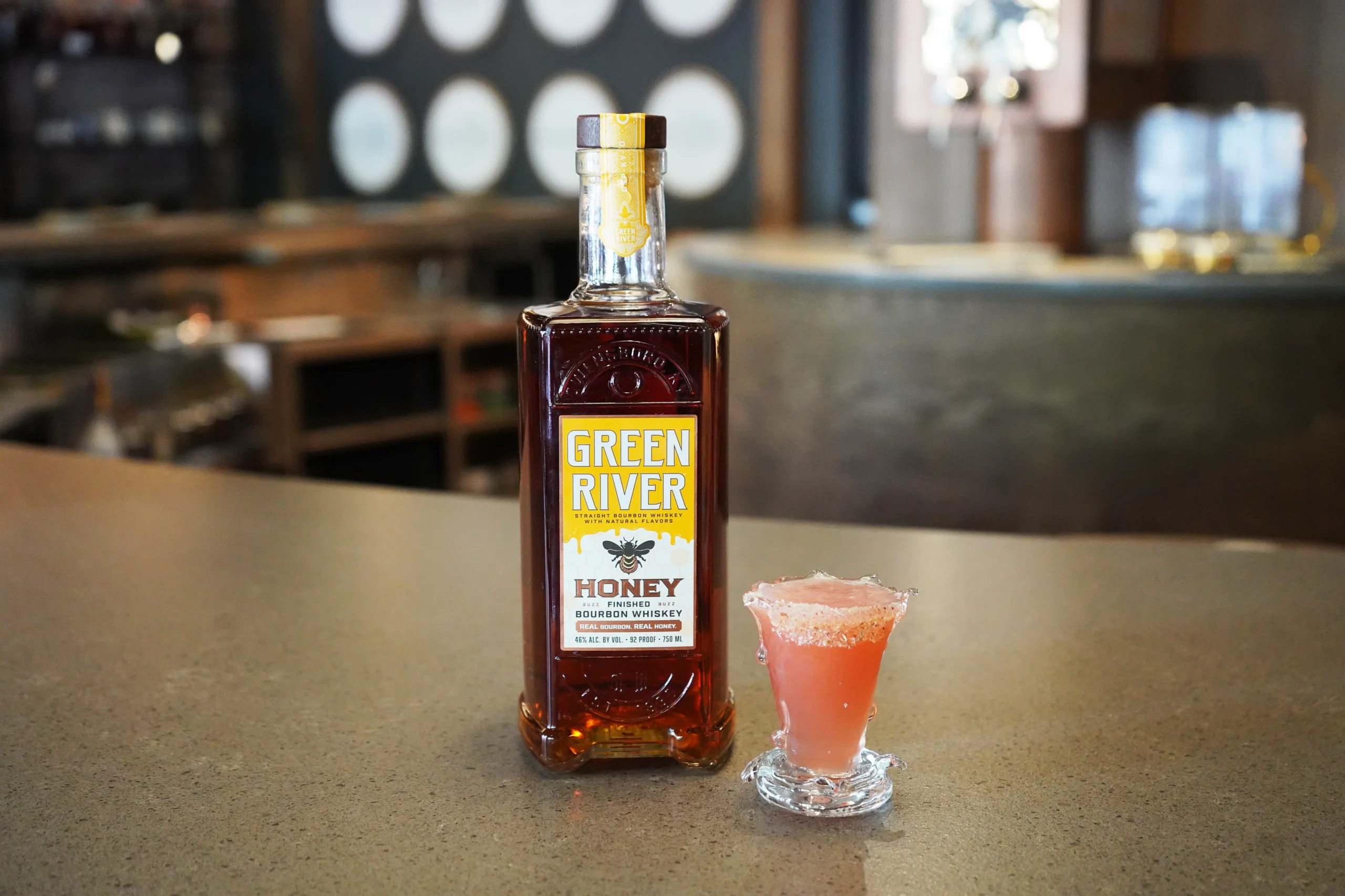 Green River Honey bourbon bottle with a served cocktail on a bar counter. 