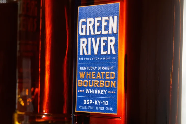 Green River Kentucky Straight Wheated Bourbon bottle with blue label under red neon light.